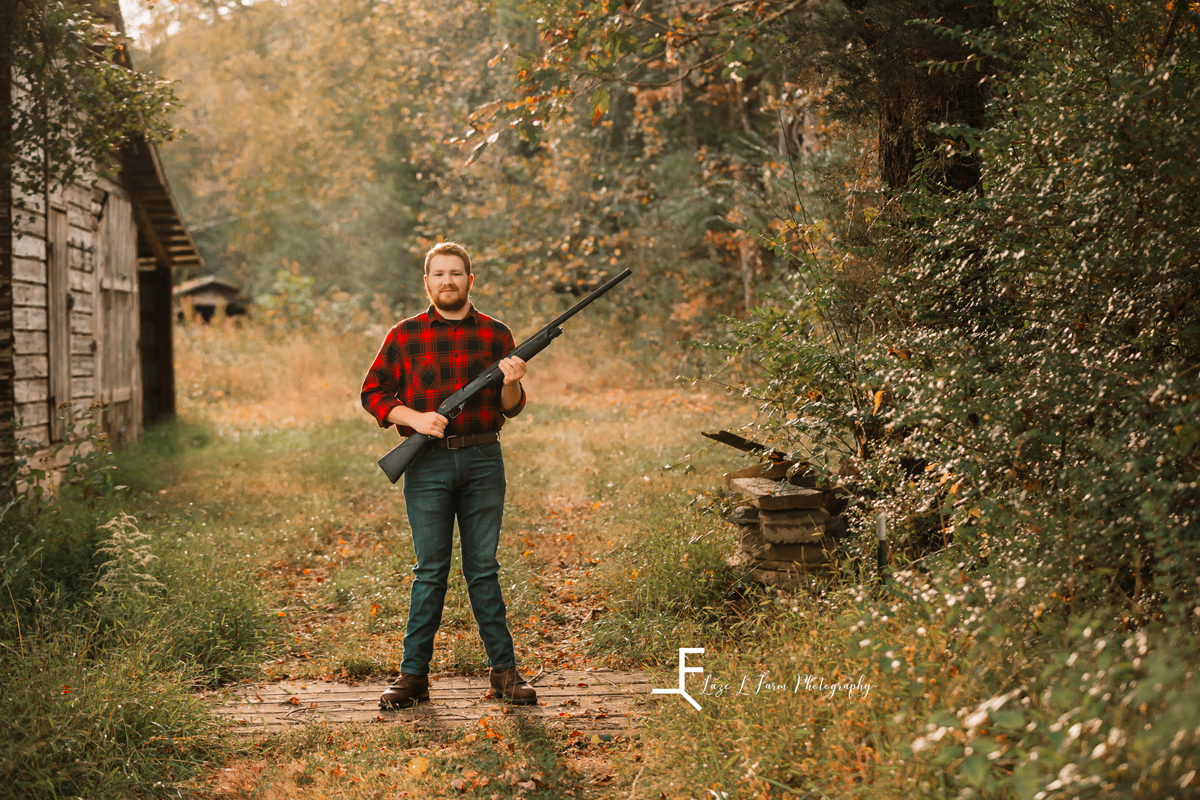 Laze L Farm Photography | Senior Pictures | Taylorsville NC | holding the gun with the landscape in the back