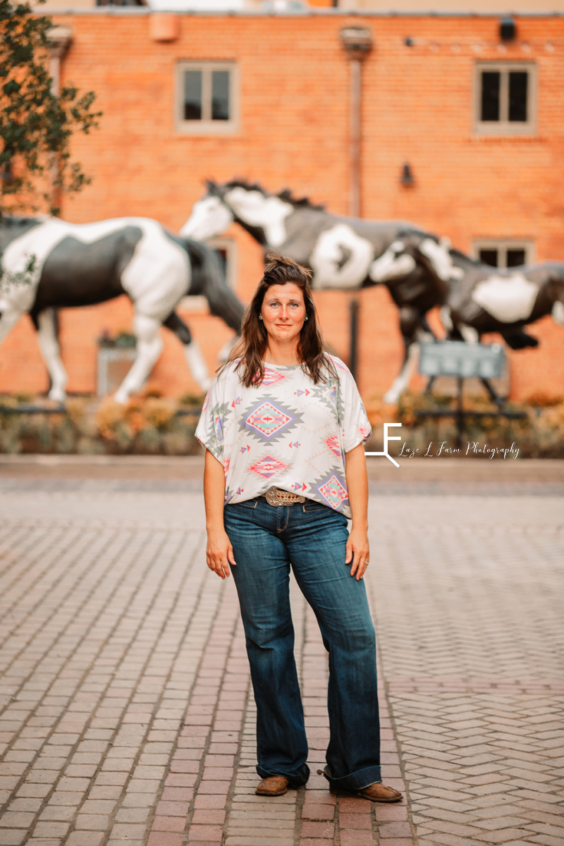 girl in aztec print shirt in front of horses 