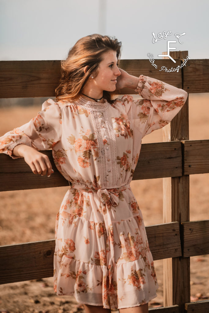 girl in flower print dress against fence
