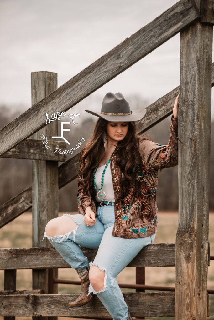 cowgirl in vintage jacket on wooden fence