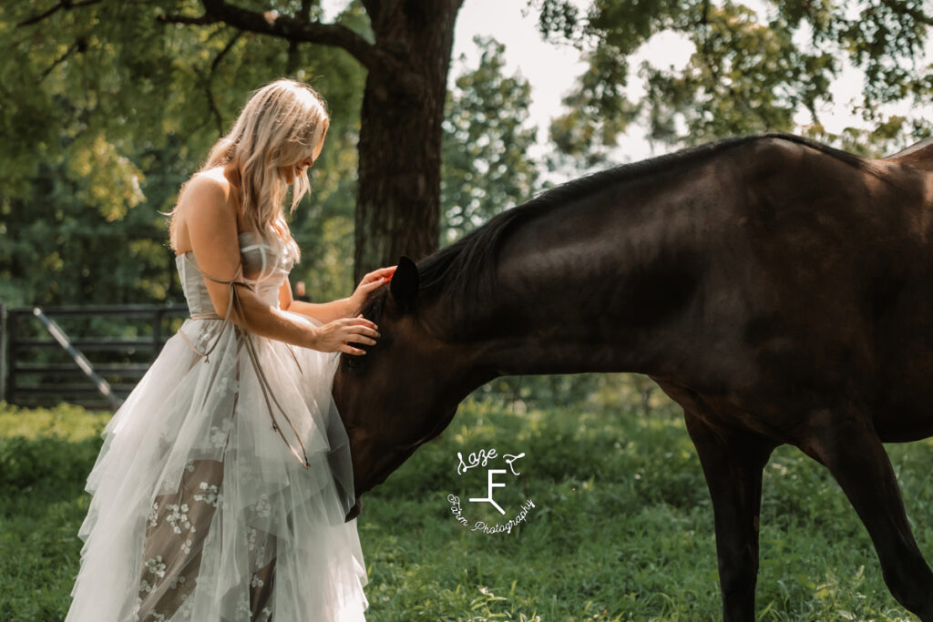 model with black horse in tan and white dress