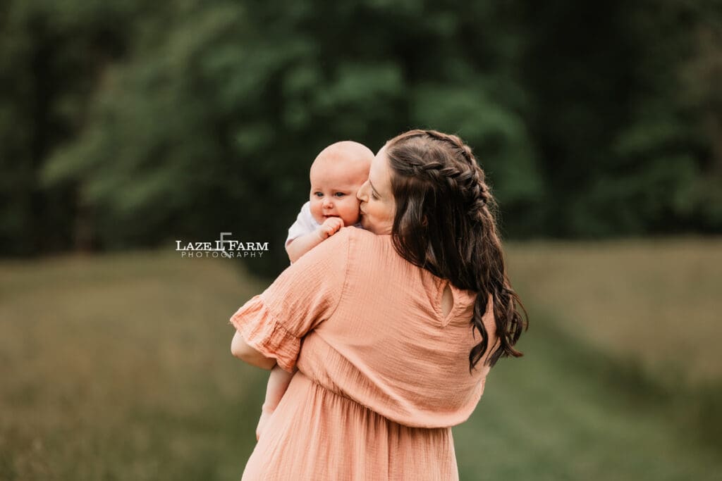 mom holding son on shoulder and kissing him on the cheek