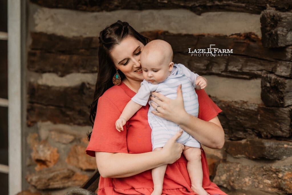 mom and son sitting under a cabin for family pictures