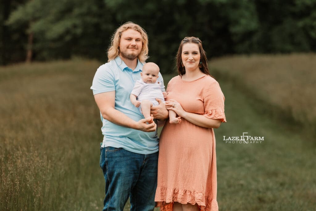 mom, dad, and son standing in a field for family pictures