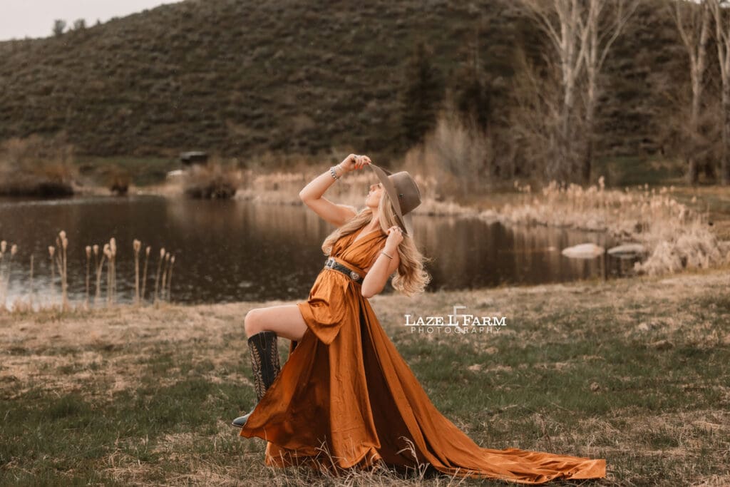 cowgirl in a copper dress in front of a pond