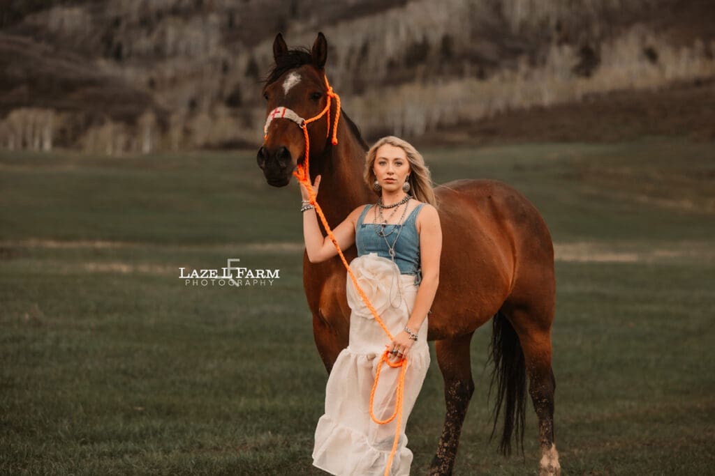 girl holding her horse in front of the mountains