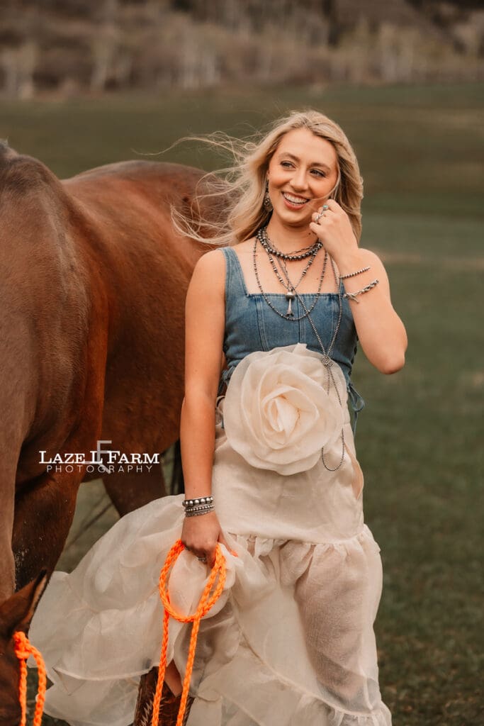 girl holding her horse in a big field
