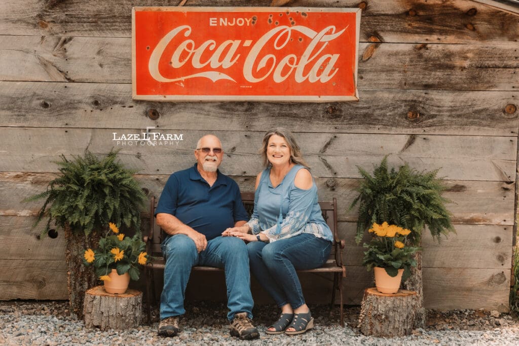 couple sitting on a bench in front of their old barn for family pictures