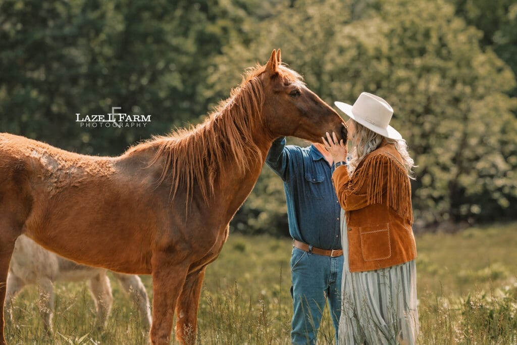 couple standing with their horses at sunset on the mountain for an equine photoshoot