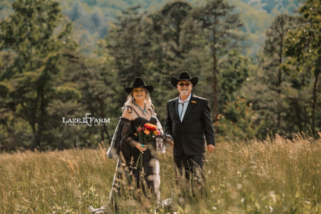 couple holding hands in a big field at sunset with the mountains behind them during a photoshoot