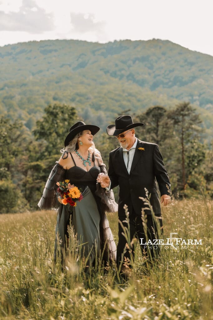 couple holding hands in a big field at sunset with the mountains behind them during a photoshoot