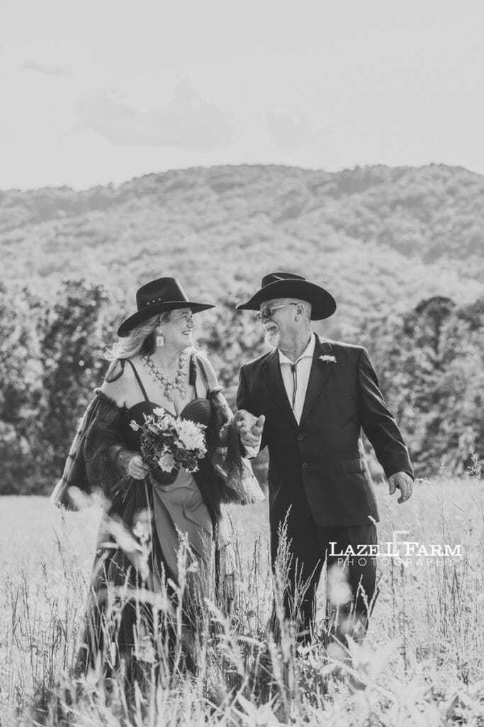 couple holding hands in a big field at sunset with the mountains behind them during a photoshoot