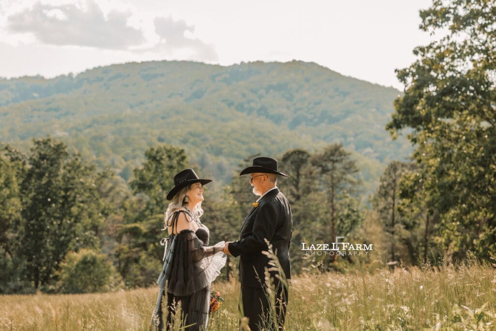 couple holding hands in a big field at sunset with the mountains behind them during a photoshoot