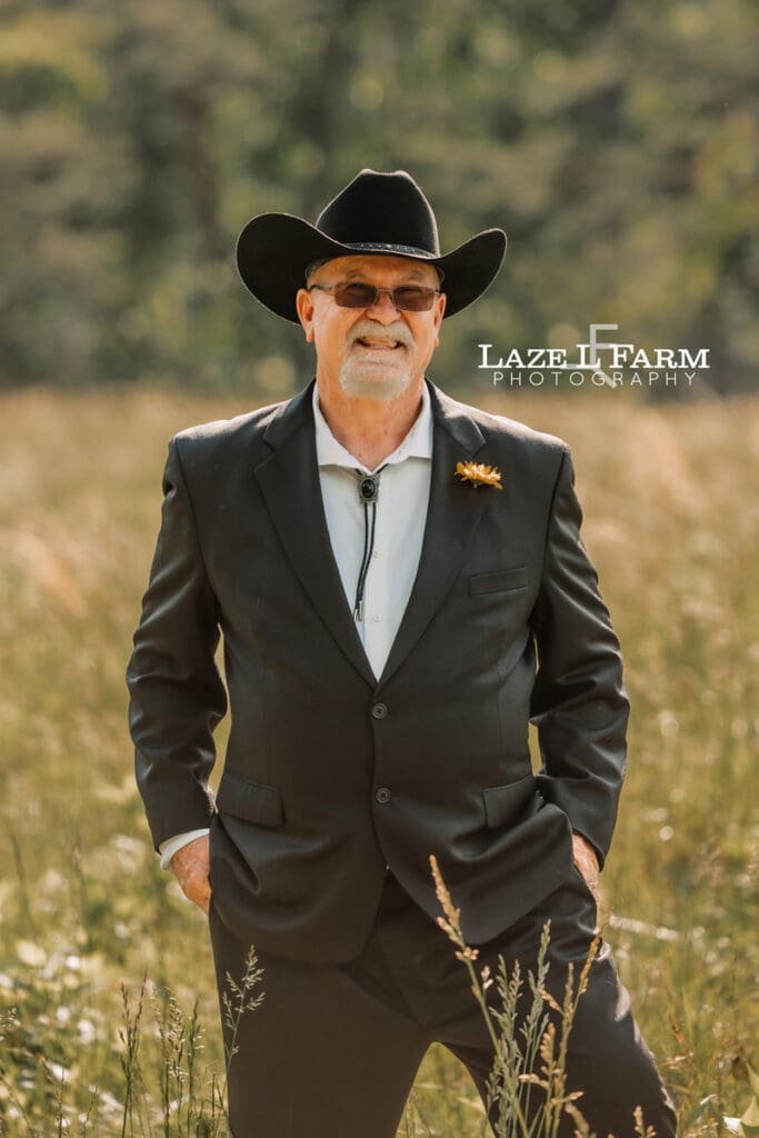 cowboy standing in a field at sunset for a photoshoot