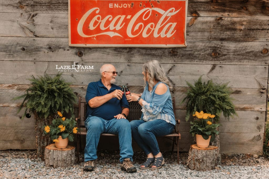 couple sitting on a bench in front of their old barn for family pictures