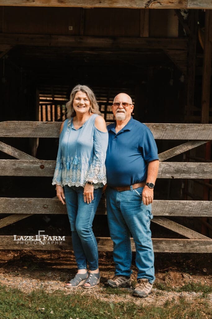 couple standing in front of their barn during family pictures
