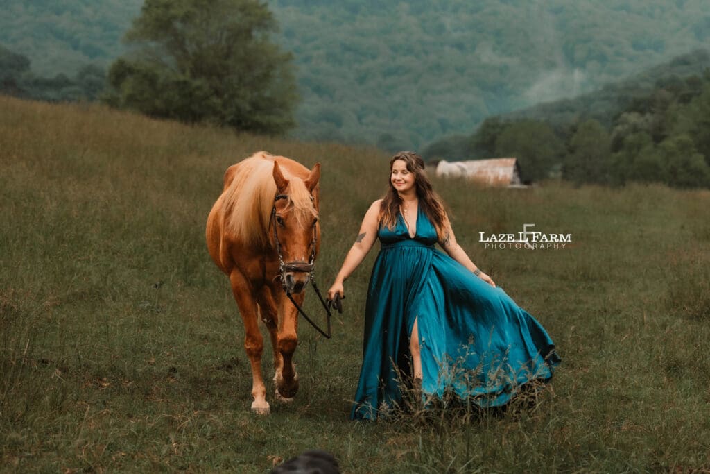 girl walking with her horse in a field with mountains