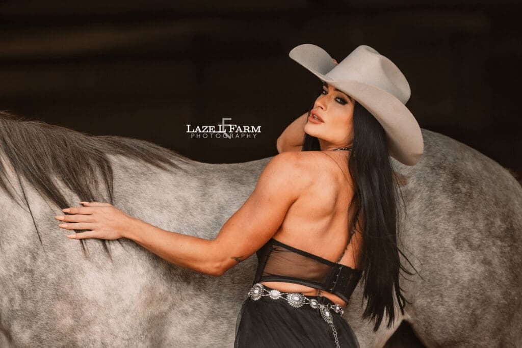 cowgirl leaning against the horse looking to the side