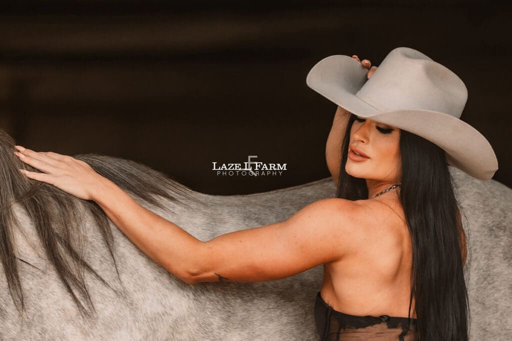 cowgirl leaning up against the horse looking over her shoulder