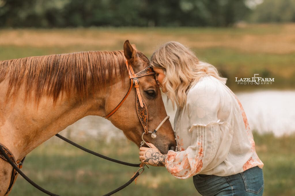cowgirl kissing her horse on the forehead