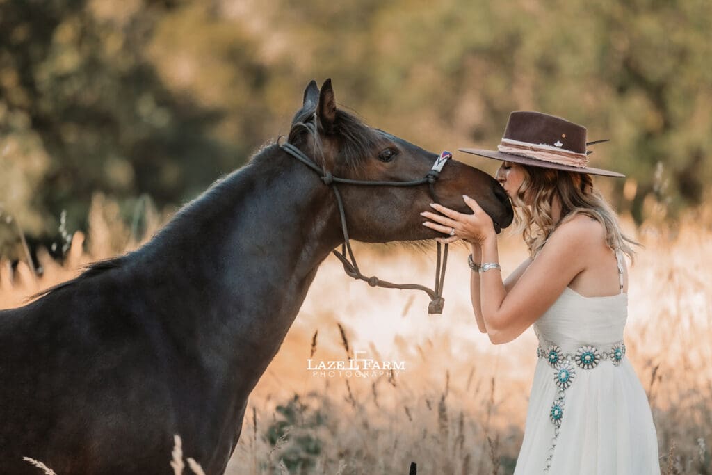 cowgirl kissing her horse on the nose