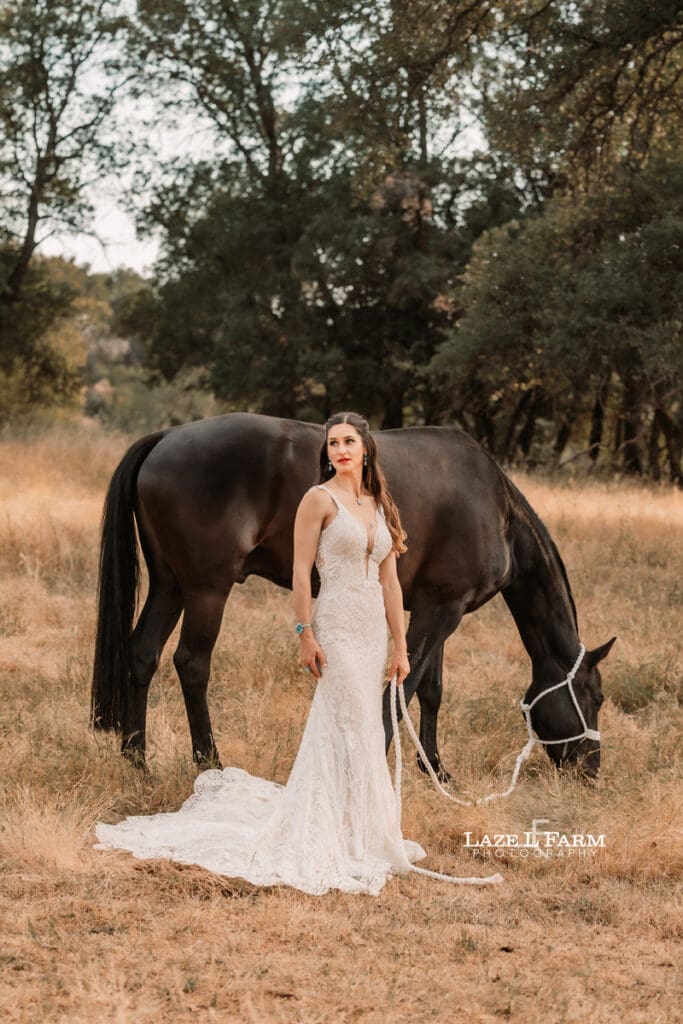 cowgirl in a wedding dress with her horse in a field
