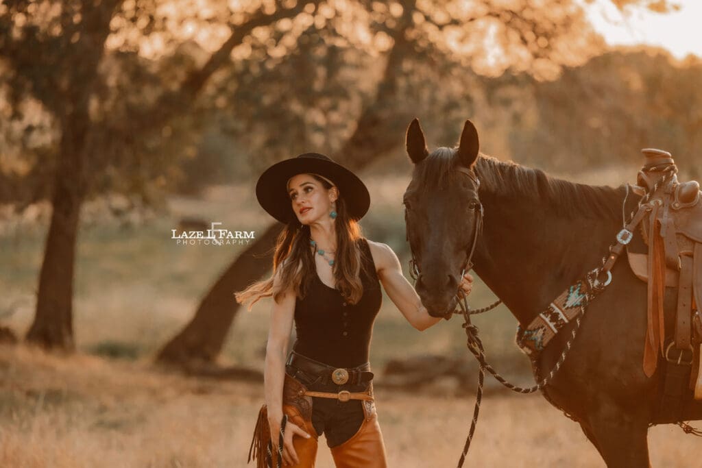 cowgirl standing beside of a horse in a field
