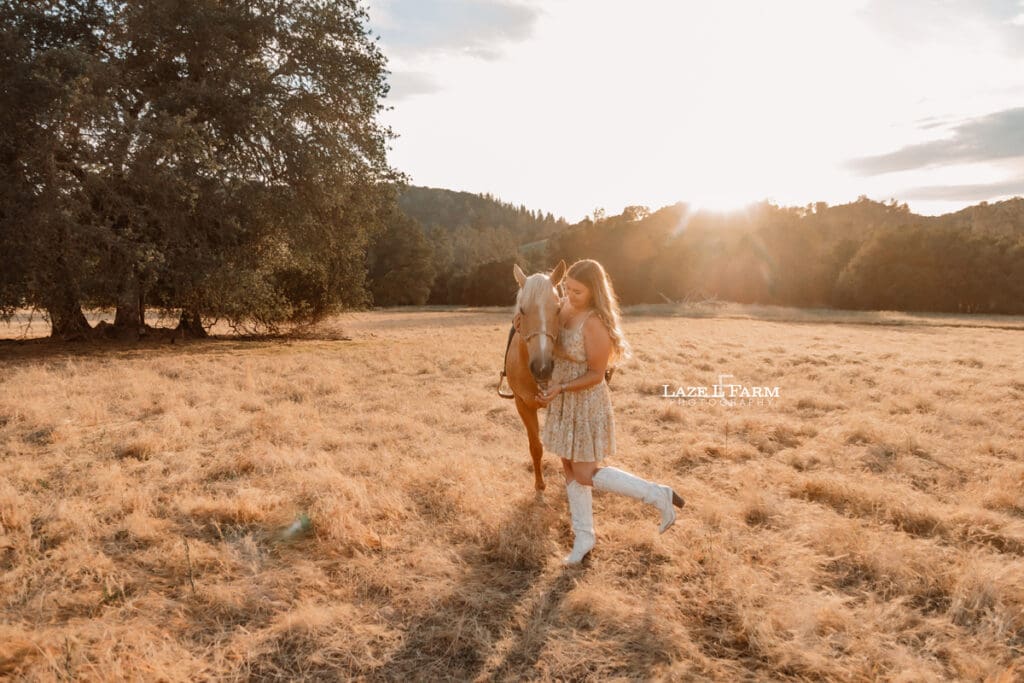 a girl with her horse in a field at sunset