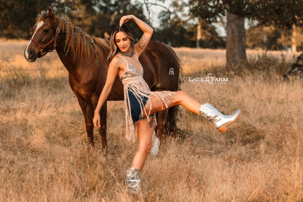 cowgirl with a sparkly dress and boots in a field with a horse