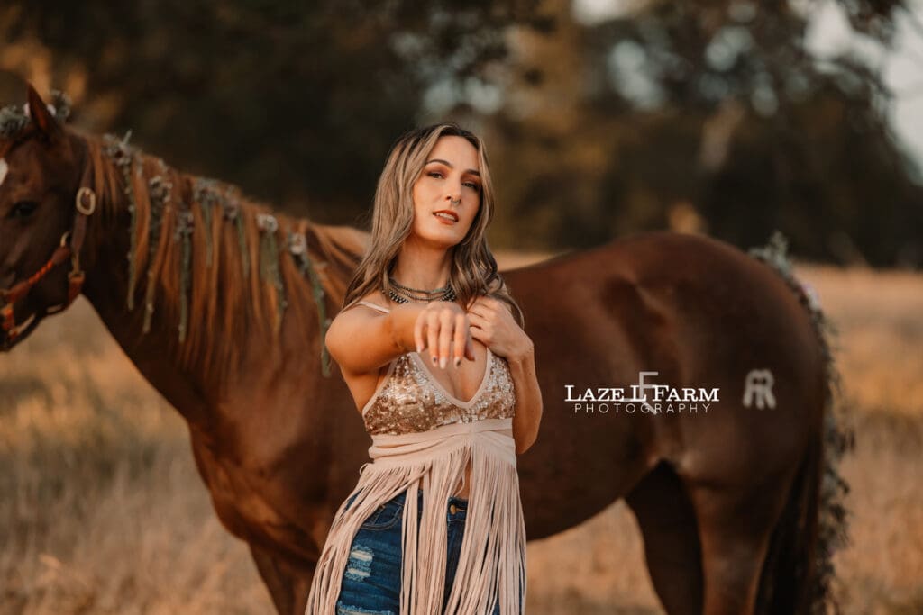 cowgirl with a sparkly dress and boots in a field with a horse