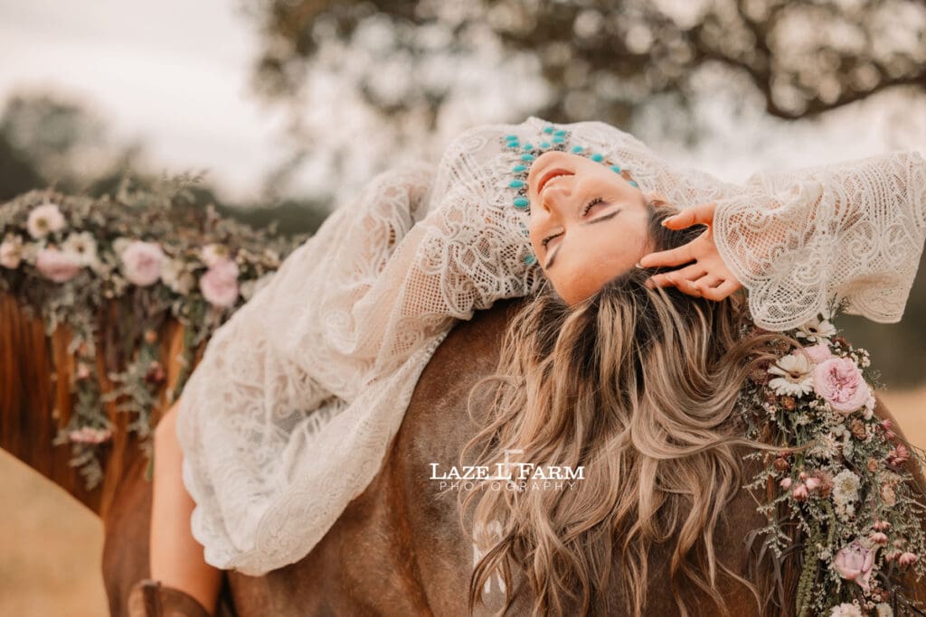 cowgirl laying on the back of a horse in a lacy dress