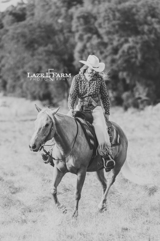 cowgirl trotting her horse in a field