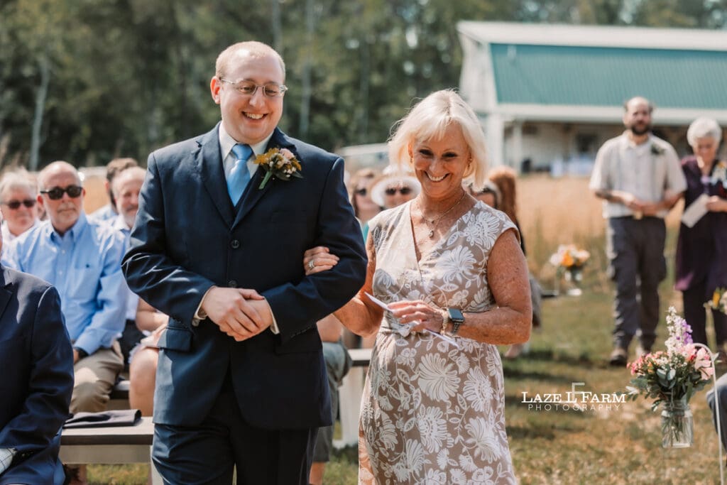 Groom walking down the aisle with family during their wedding at Woodside Farm in Graham, NC with pictures by Laze L Farm Photography