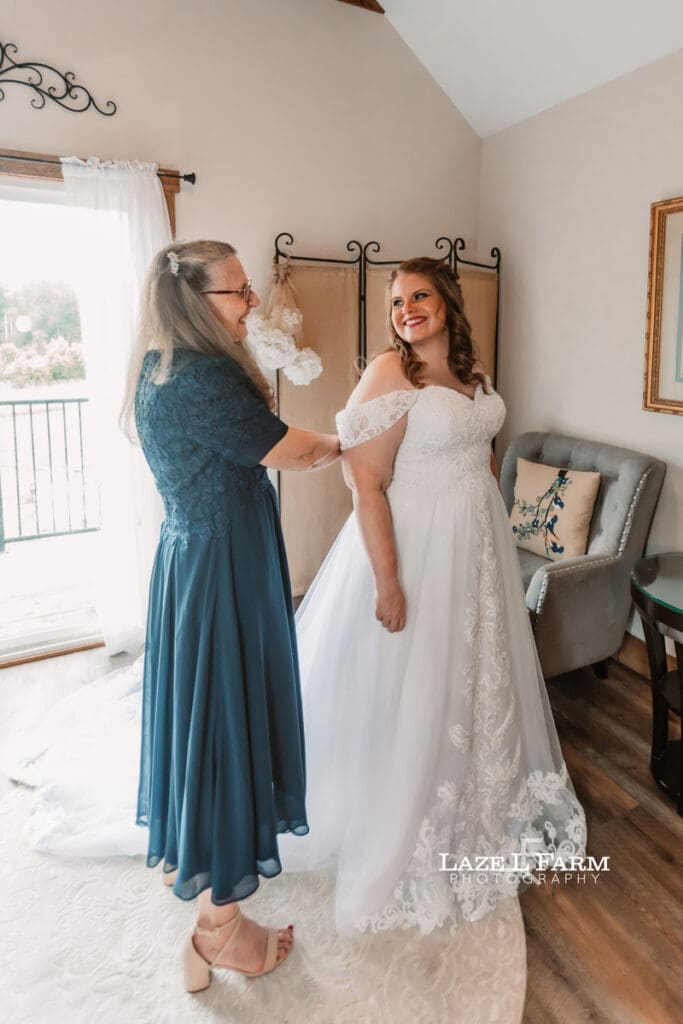 Mother of the bride helping the bride with her dress during her wedding at Woodside Farm in Graham, NC with pictures by Laze L Farm Photography