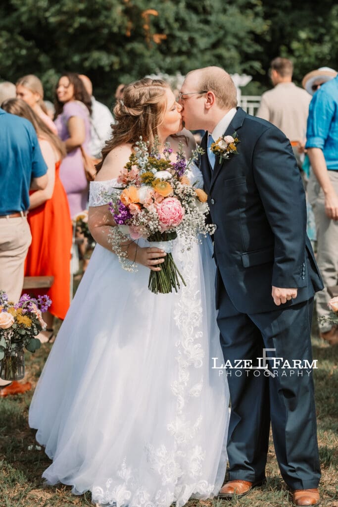 Wedding couple kissing at the end of the aisle after getting married at Woodside Farm in Graham NC with pictures by Laze L Farm Photography