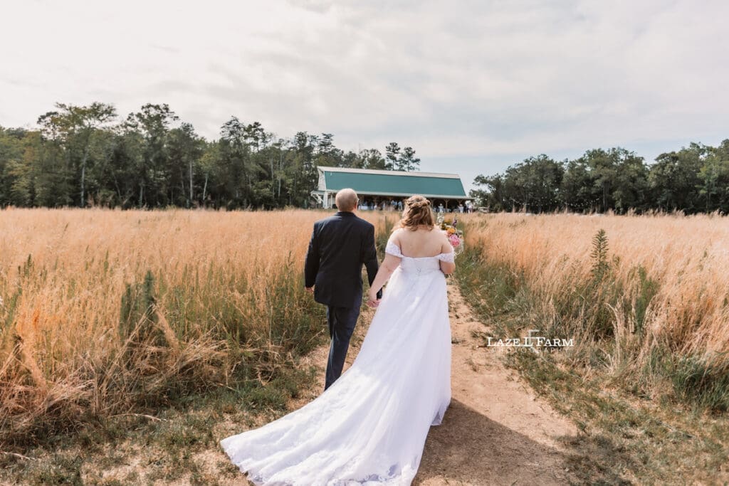 Bride and Groom walking toward their reception after the wedding at Woodside Farm in Graham, NC with pictures by Laze L Farm Photography