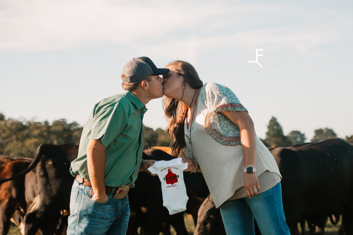 Laze L Farm Photography | Farm Session | Taylorsville NC | Couple kissing and holding onesie