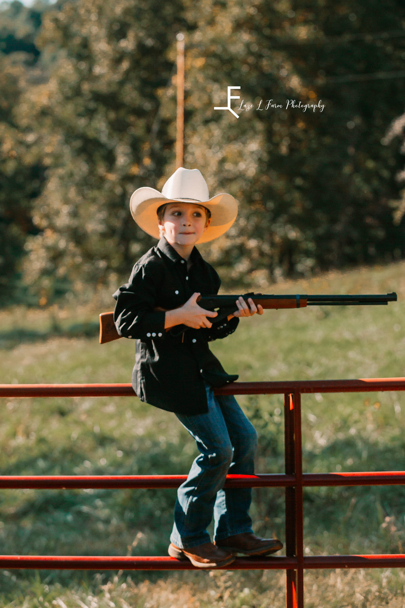 Laze L Farm Photography | Farm Session | Taylorsville NC | holding the gun and sitting on the fence