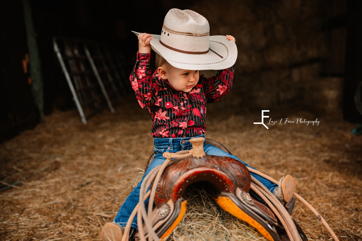  Laze L Farm Photography | Farm Session | Taylorsville NC | holding her hat on the saddle