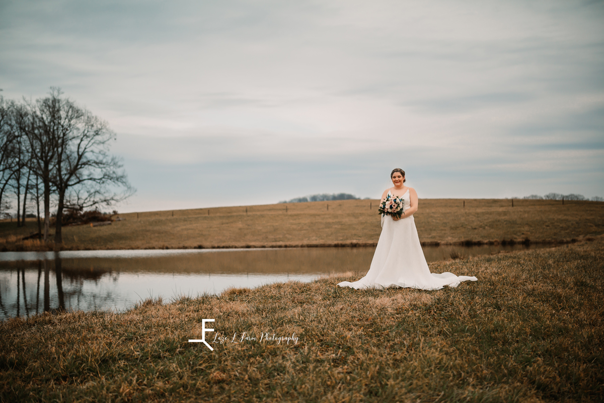 Laze L Farm Photography | Bridal Session | The Emerald Hill | in wedding dress standing by lake