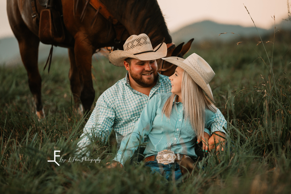 Laze L Farm Photography | Cowboy Couple | Taylorsville NC | happy couple looking at each other while sitting on grass