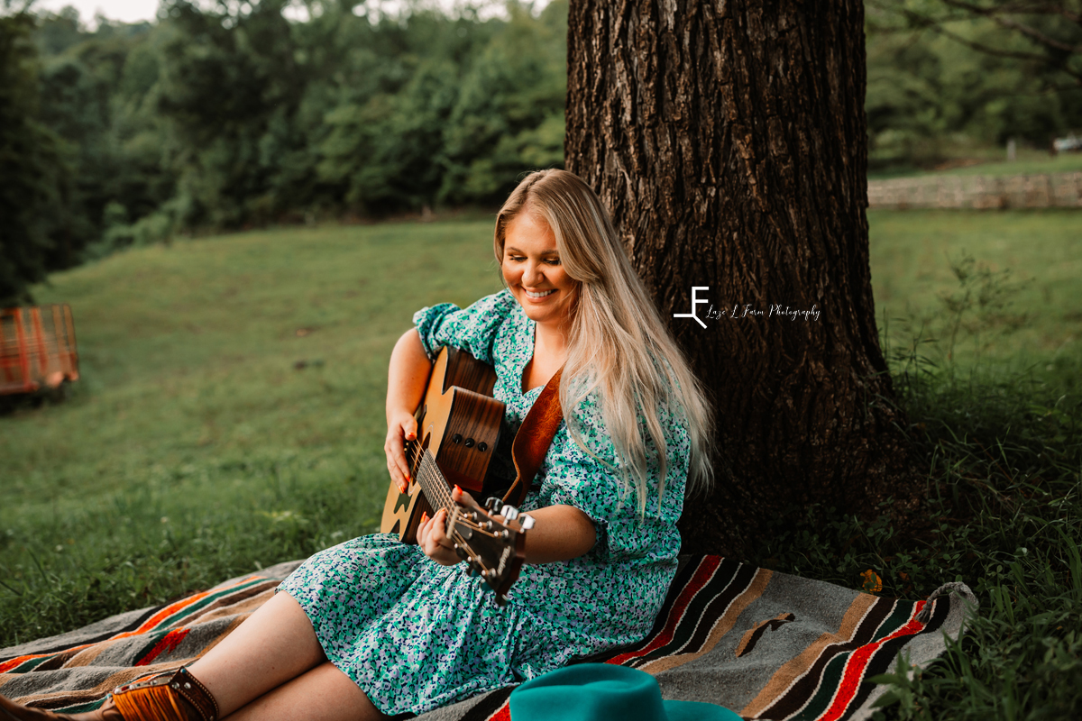 girl playing guitar against a tree