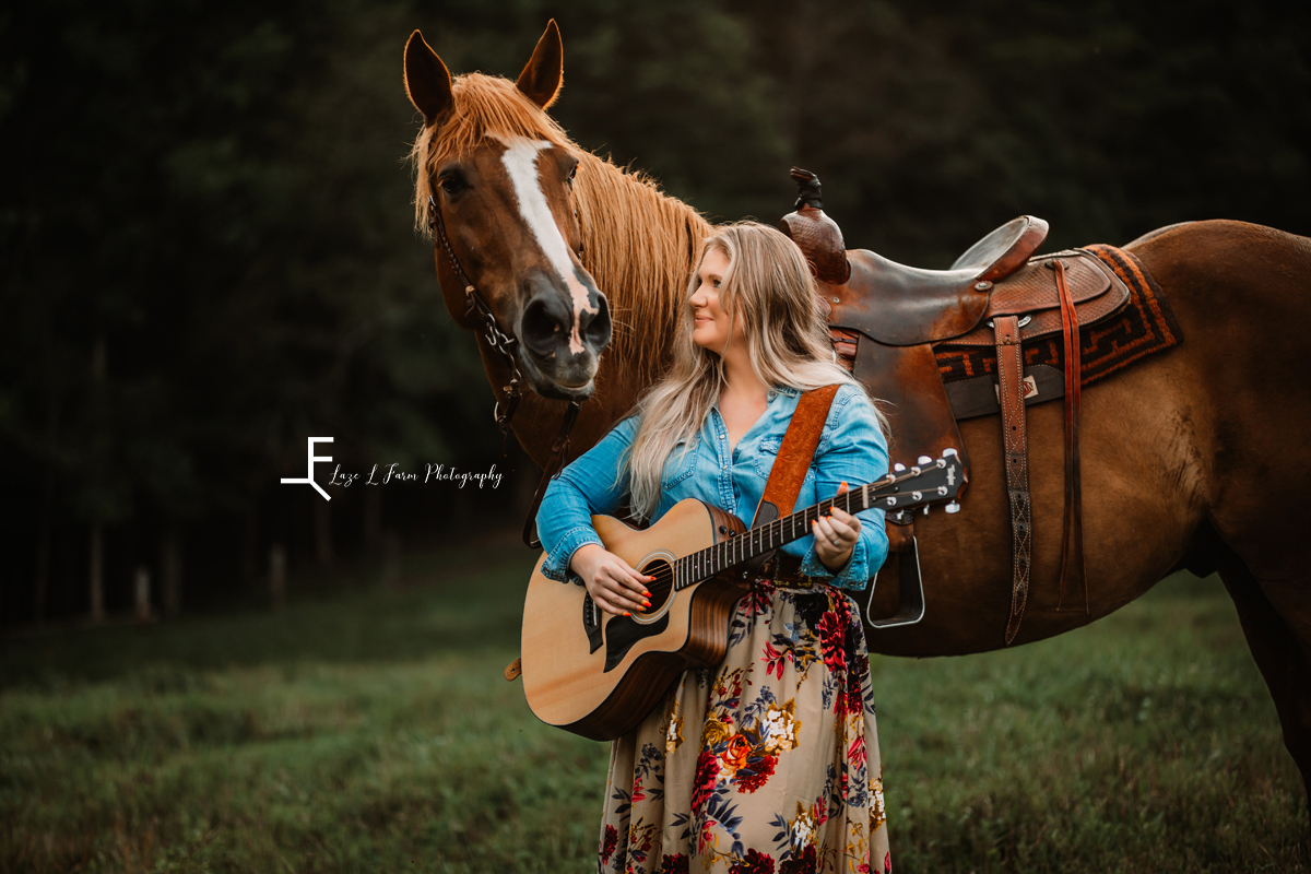 girl playing guitar standing with horse 