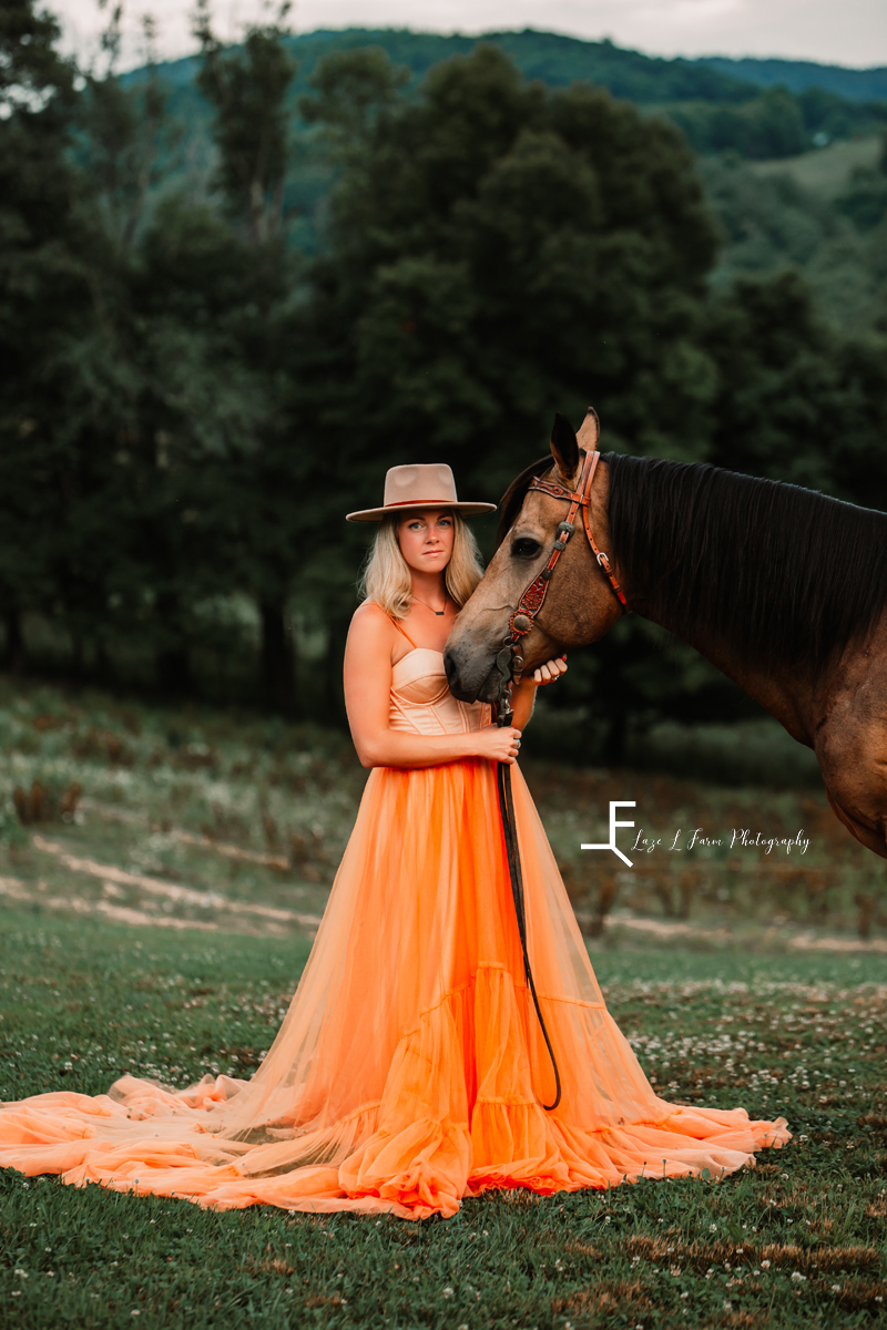 girl in orange dress in a hat with horse