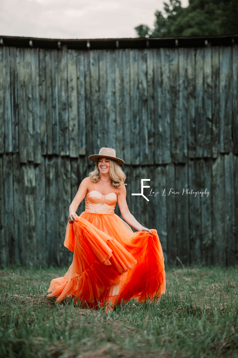 girl in orange dress in front of barn