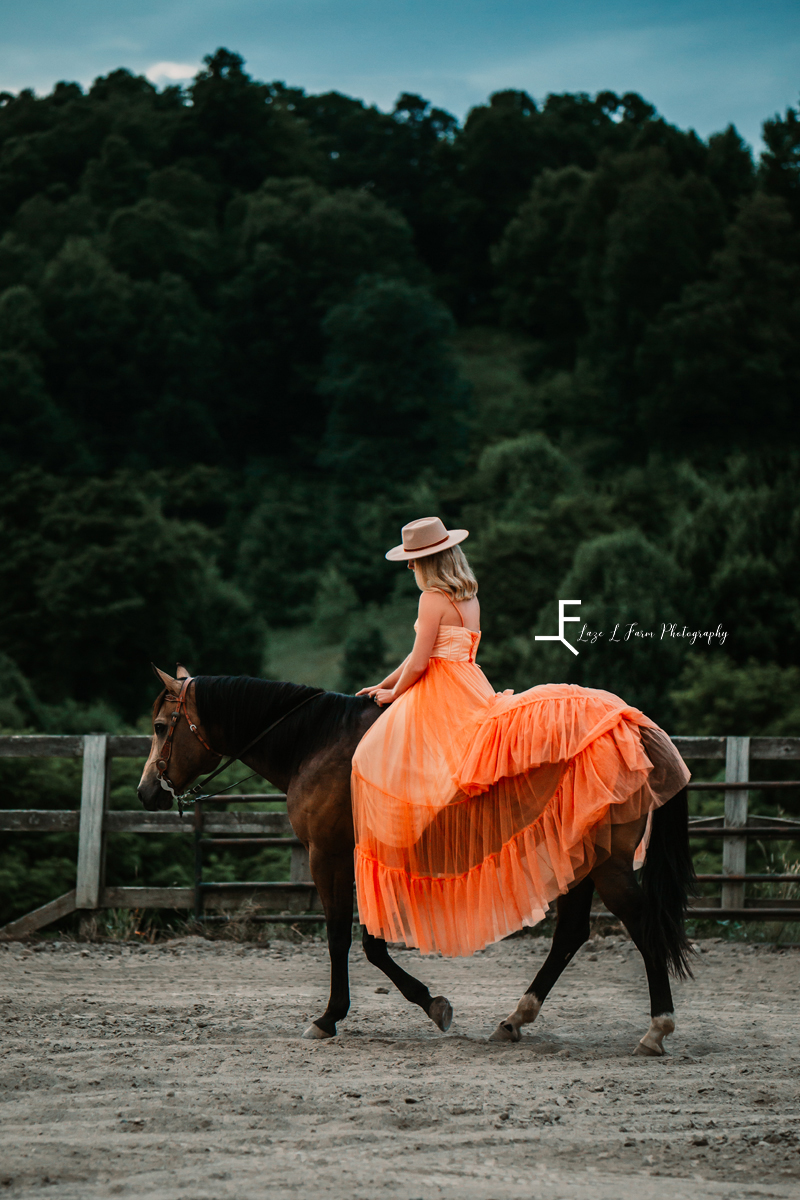 girl in orange dress with hat on horse 