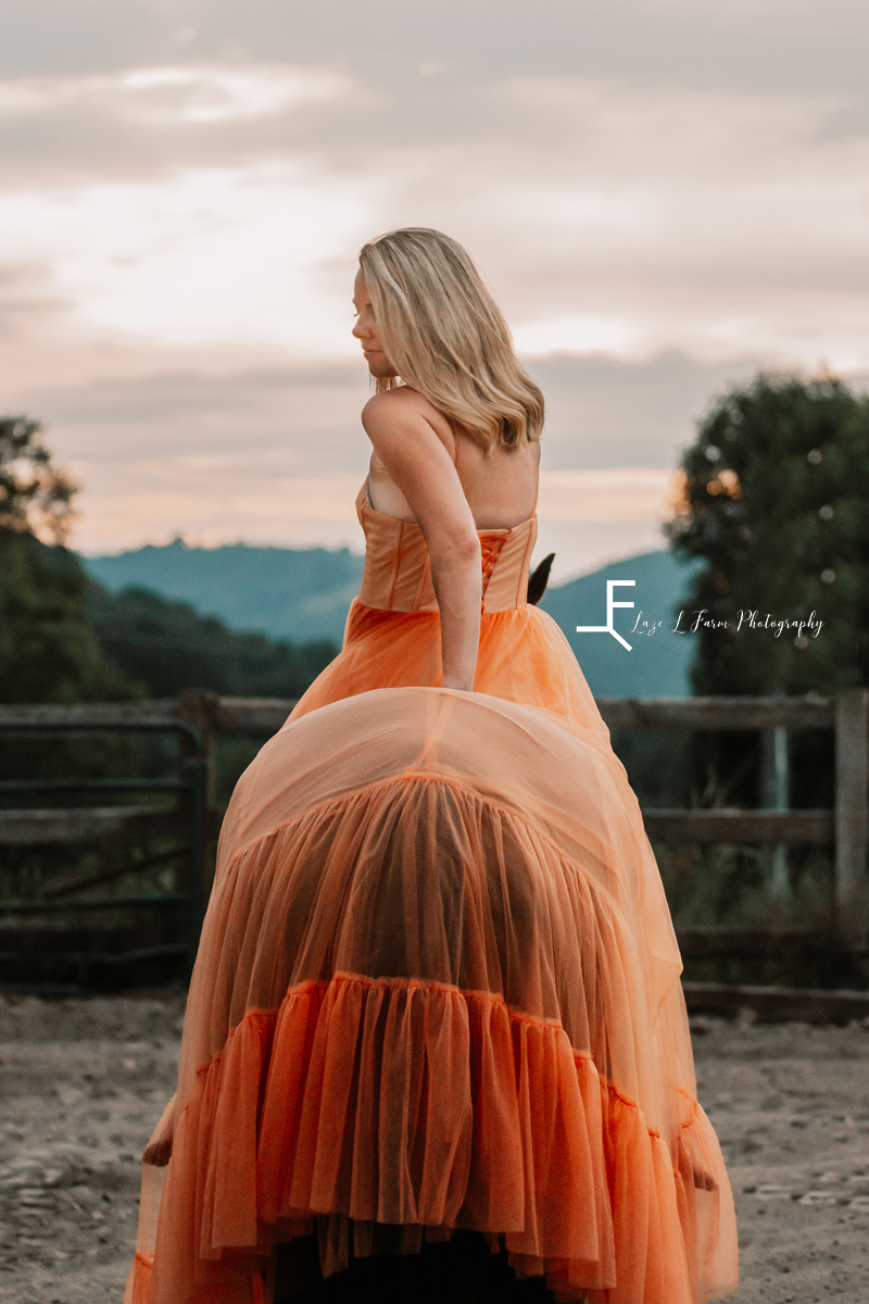 girl in orange dress on horse facing away from camera