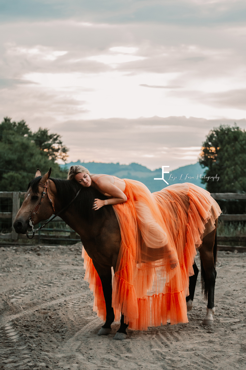 girl in orange dress laying on horse