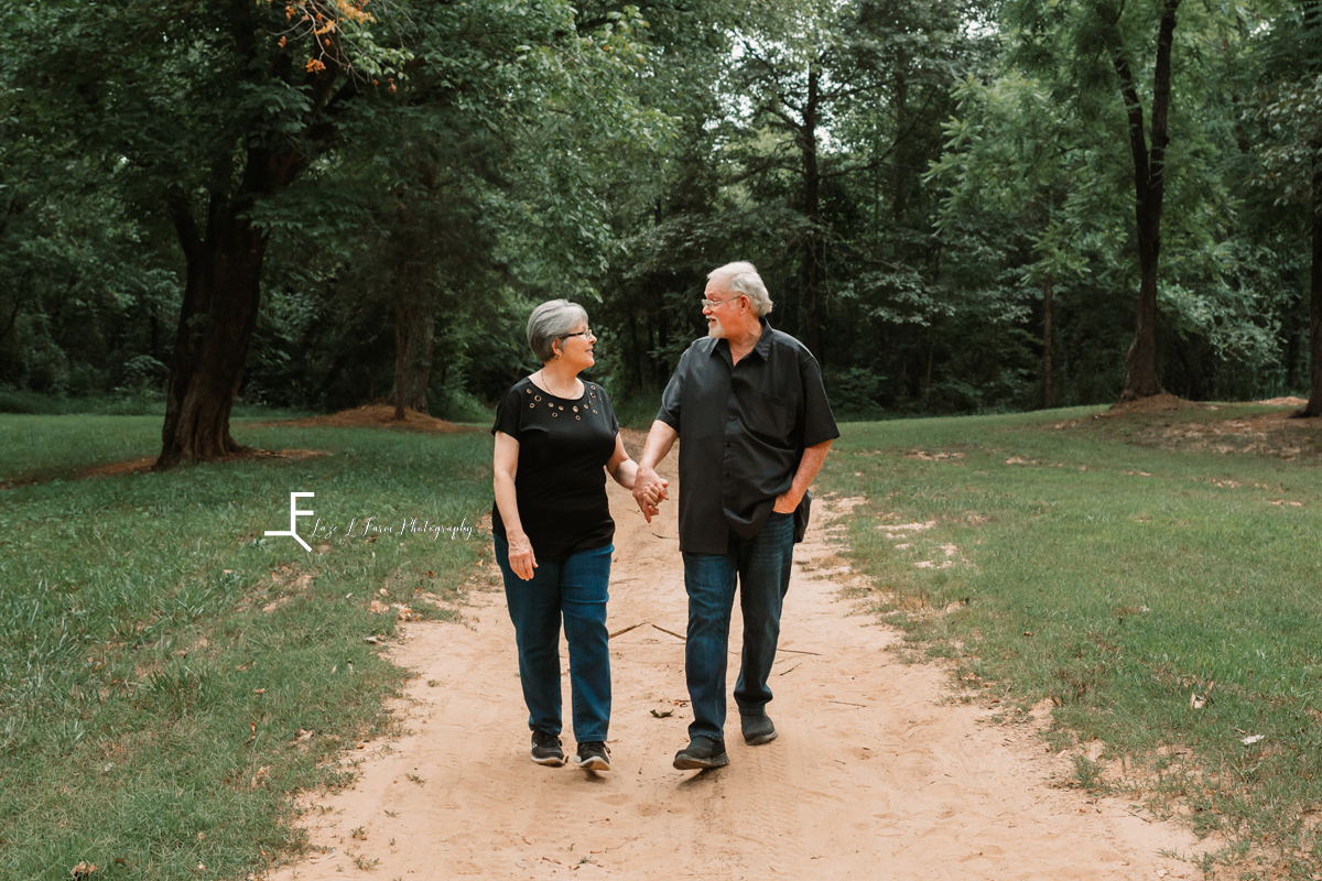 Husband and wife walking down dirt road holding hands