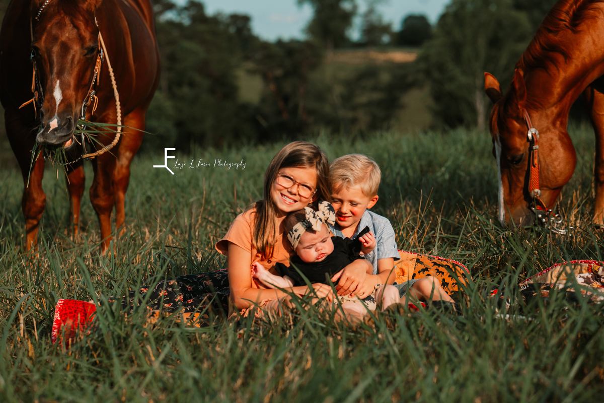 3 kids with horses in the background